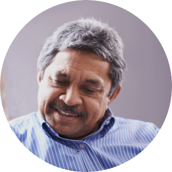 An older man in a blue striped shirt smiling while looking down